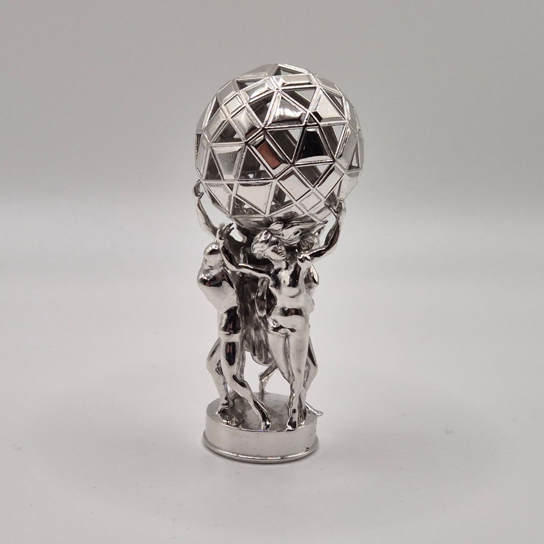 Small figurine holding a sphere in chrome plated brass, highly reflective finish
